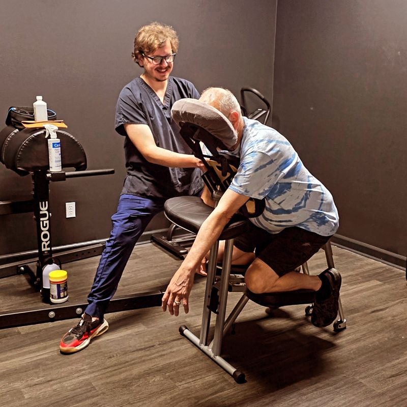Alex Adamczyk, LMT, giving a seated chair massage at Hustle House in Woodstock